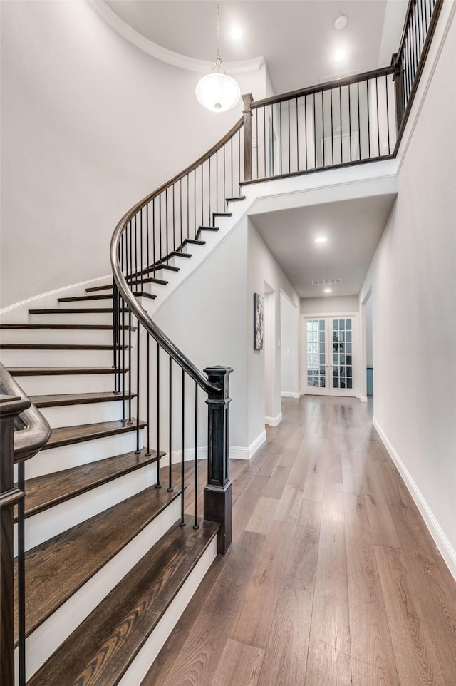 entryway with french doors, stairs, baseboards, wood finished floors, and a towering ceiling