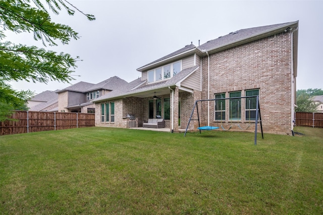 rear view of property featuring brick siding, ceiling fan, a fenced backyard, a patio area, and a lawn