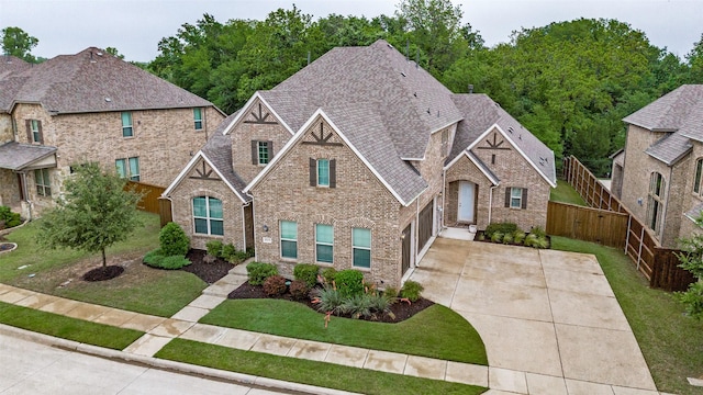 view of front of property featuring fence, an attached garage, a front lawn, brick siding, and concrete driveway