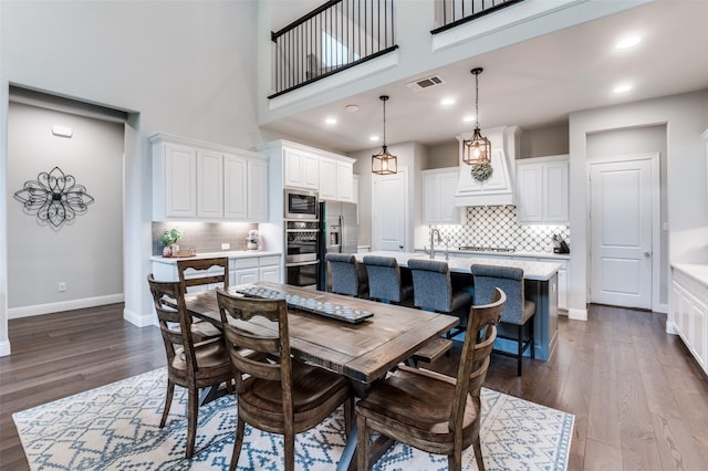 dining area with baseboards, dark wood-type flooring, a towering ceiling, and visible vents