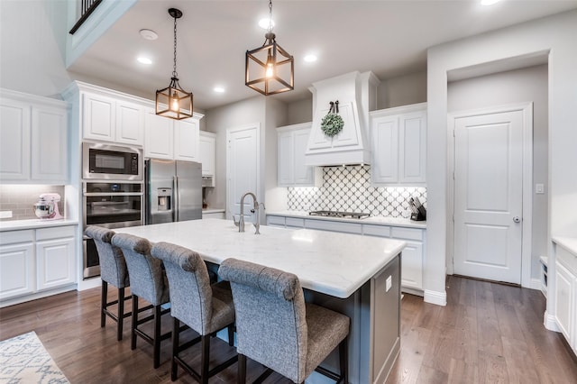 kitchen featuring decorative backsplash, a kitchen breakfast bar, dark wood-style floors, white cabinets, and appliances with stainless steel finishes