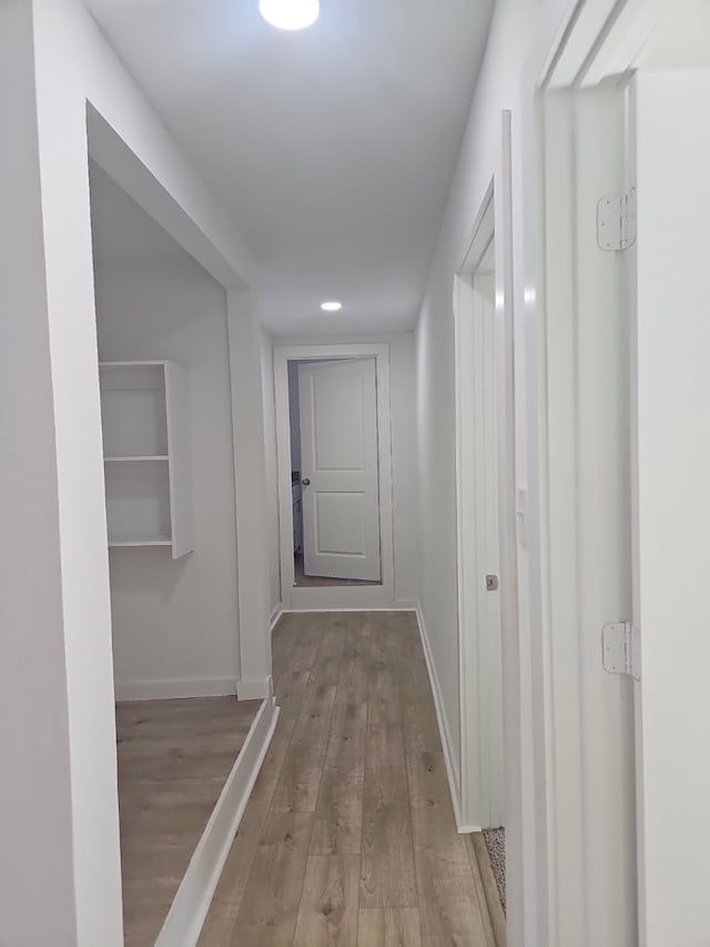 hall featuring baseboards, recessed lighting, and wood finished floors