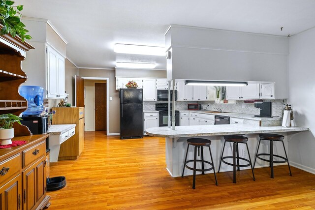 1730 W Hull St, Denison, TX 75020 - kitchen featuring tasteful backsplash, a peninsula, white cabinetry, light wood-type flooring, and black appliances