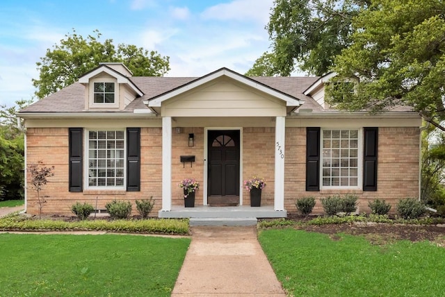 view of front of property featuring a porch, brick siding, and a front yard