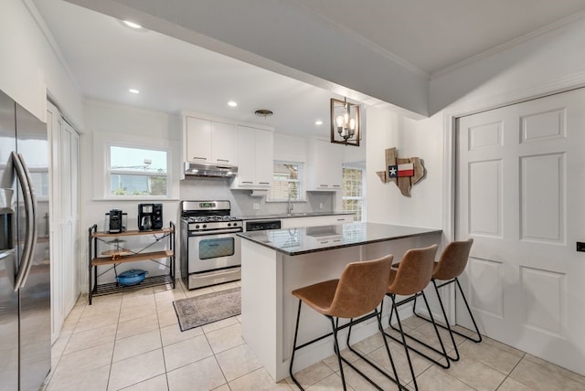 kitchen featuring ornamental molding, a breakfast bar area, white cabinetry, under cabinet range hood, and stainless steel appliances