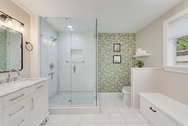 bathroom featuring a stall shower, vanity, baseboards, toilet, and wallpapered walls