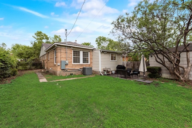 rear view of property with a lawn, brick siding, fence, cooling unit, and a patio
