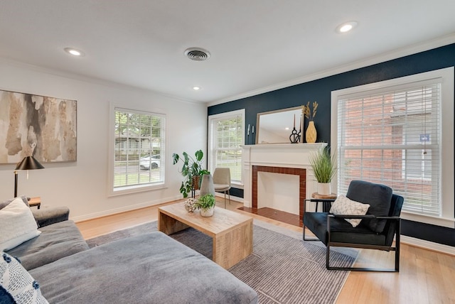 living room featuring crown molding, visible vents, wood finished floors, and a fireplace