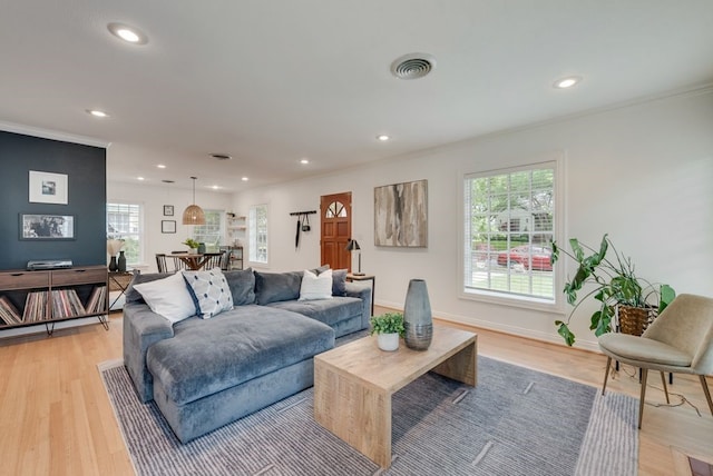 living room featuring visible vents, baseboards, light wood finished floors, ornamental molding, and recessed lighting