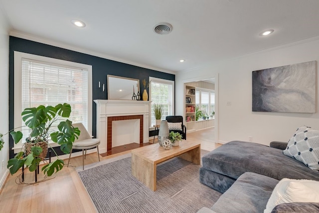 living room featuring crown molding, recessed lighting, a fireplace with flush hearth, wood finished floors, and visible vents