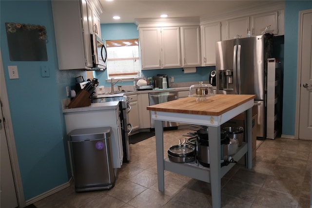 kitchen featuring appliances with stainless steel finishes, open shelves, white cabinets, recessed lighting, and butcher block countertops