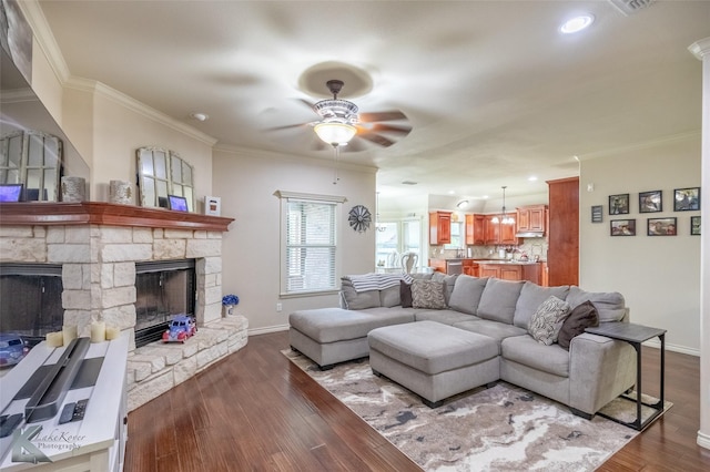 living room featuring a fireplace, crown molding, baseboards, and a ceiling fan