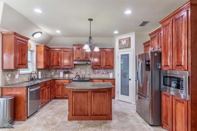 kitchen with a sink, visible vents, appliances with stainless steel finishes, a kitchen island, and tasteful backsplash