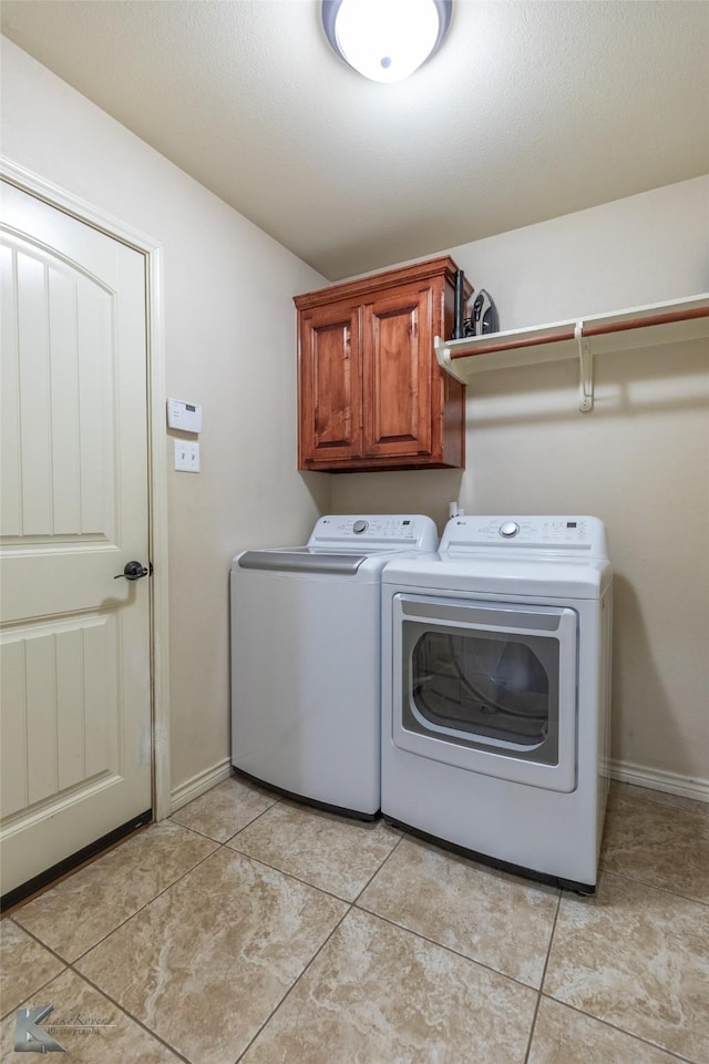 laundry room with washer and dryer, cabinet space, baseboards, and light tile patterned floors