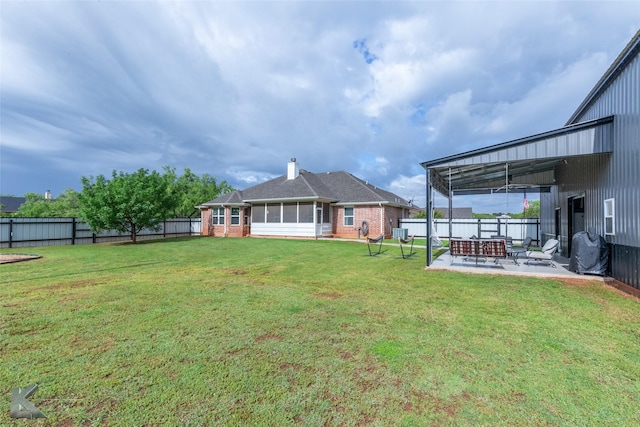 back of house featuring a patio area, brick siding, a fenced backyard, a lawn, and a sunroom