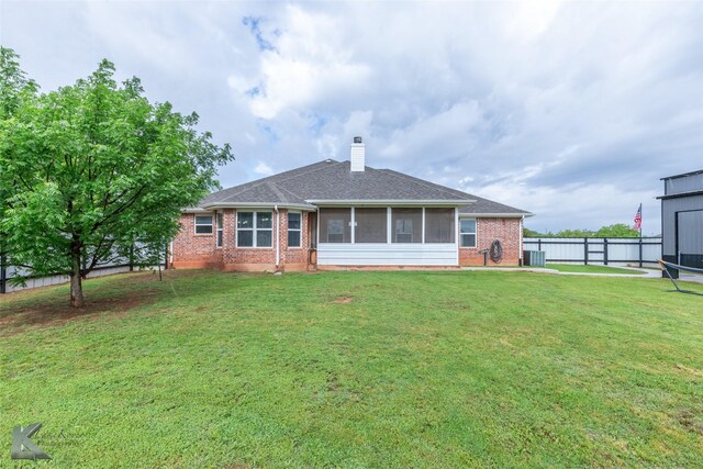 rear view of house with fence, a sunroom, brick siding, and a lawn