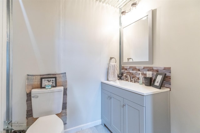 bathroom featuring vanity, toilet, backsplash, and baseboards