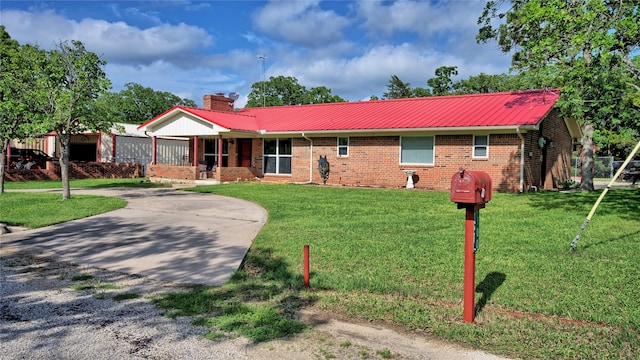 ranch-style house with brick siding, a front yard, a chimney, covered porch, and metal roof
