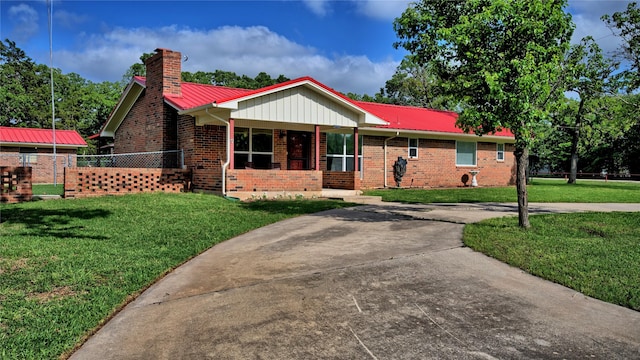 single story home featuring fence, metal roof, a front lawn, and brick siding