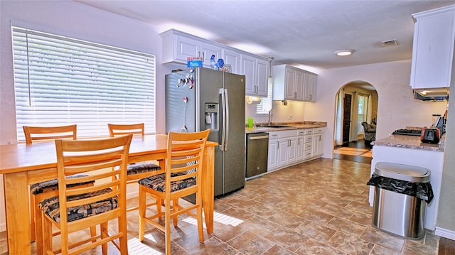 kitchen featuring visible vents, a sink, dishwashing machine, stainless steel fridge, and arched walkways
