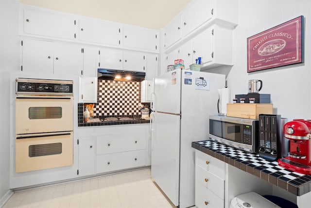 4204 Prescott Ave, Dallas, TX 75219 - kitchen featuring tile countertops, tasteful backsplash, white cabinets, under cabinet range hood, and white appliances