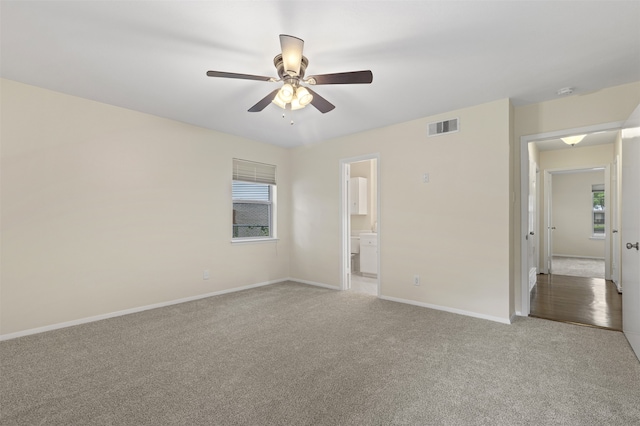 interior space featuring light colored carpet, a ceiling fan, visible vents, and baseboards