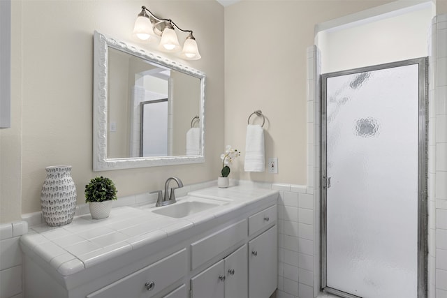 bathroom featuring vanity, tile walls, a wainscoted wall, and a shower stall