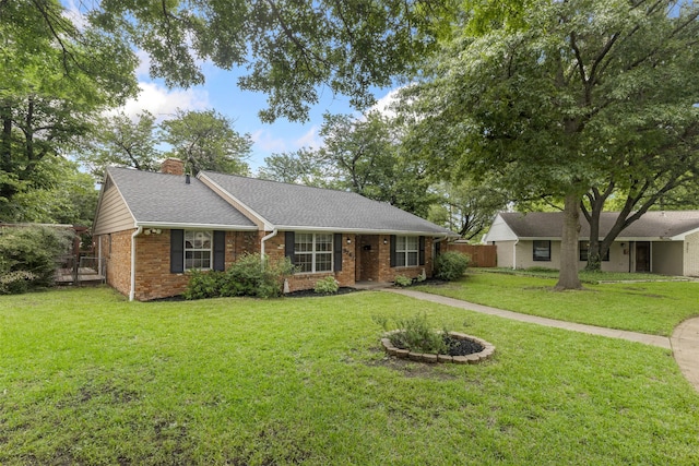 ranch-style house with brick siding, fence, a chimney, and a front lawn