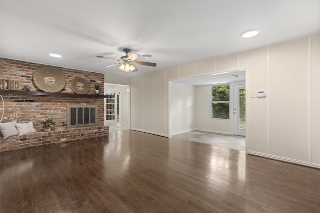 unfurnished living room featuring ceiling fan, wood finished floors, and brick wall
