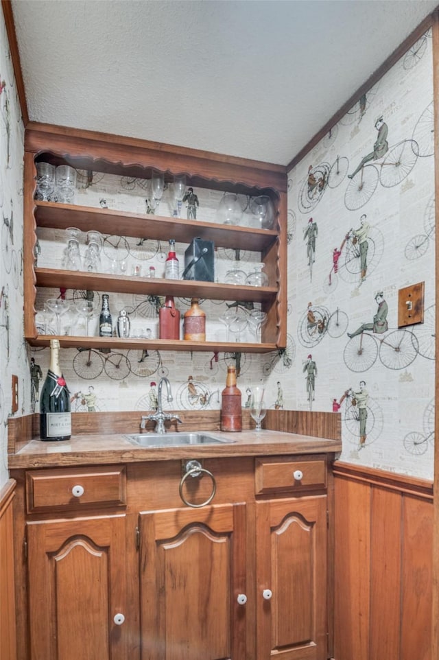 6555 Dartbrook Dr, Dallas, TX 75254 - indoor wet bar with wallpapered walls, a wainscoted wall, and ornamental molding