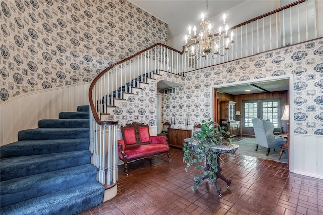 6555 Dartbrook Dr, Dallas, TX 75254 - stairs with wallpapered walls, a wainscoted wall, brick flooring, and a chandelier