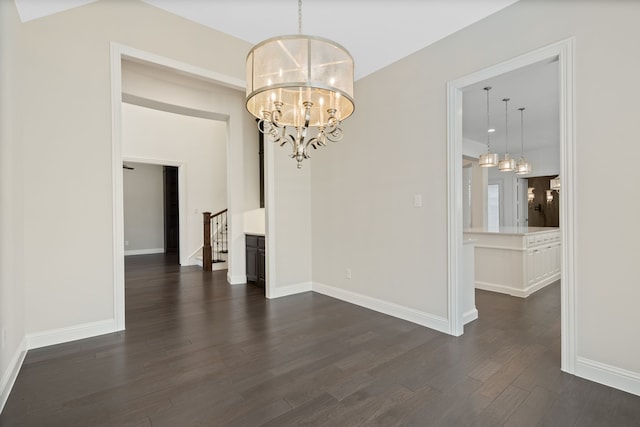 unfurnished dining area featuring baseboards, dark wood-style flooring, stairs, and a notable chandelier