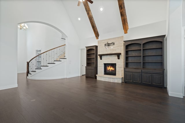 unfurnished living room featuring baseboards, high vaulted ceiling, stairway, dark wood finished floors, and ceiling fan with notable chandelier