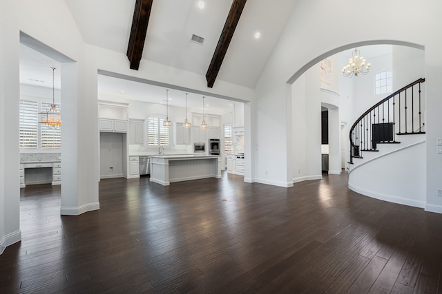 unfurnished living room featuring an inviting chandelier, stairway, high vaulted ceiling, dark wood-type flooring, and arched walkways