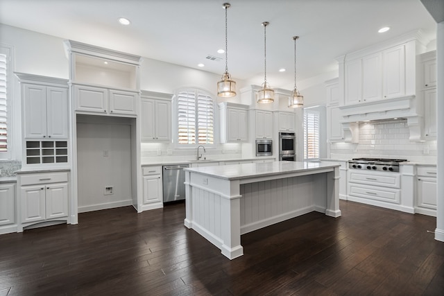 kitchen with a center island, a sink, appliances with stainless steel finishes, and tasteful backsplash