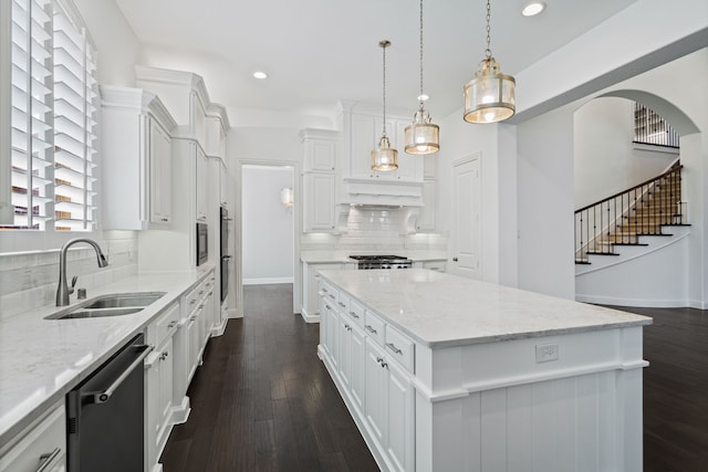 kitchen featuring white cabinets, a sink, dishwasher, tasteful backsplash, and a kitchen island