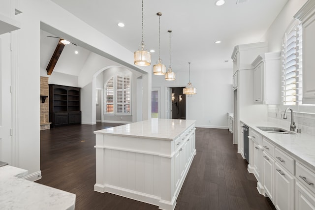 kitchen with dark wood-style flooring, light stone counters, a sink, a center island, and stainless steel dishwasher