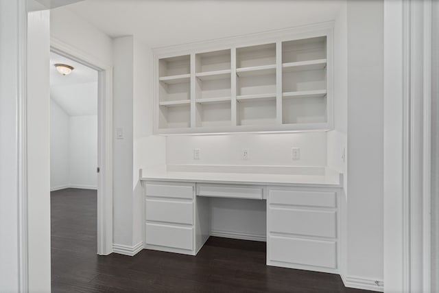 unfurnished office featuring dark wood-style flooring, baseboards, and built in study area
