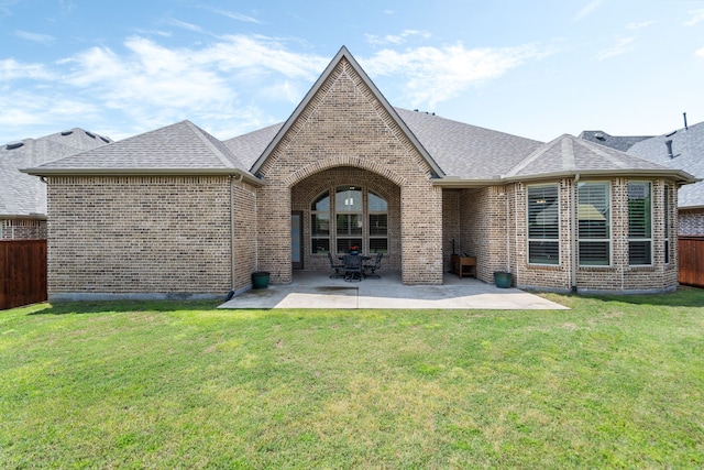 back of house with roof with shingles, fence, a yard, and brick siding