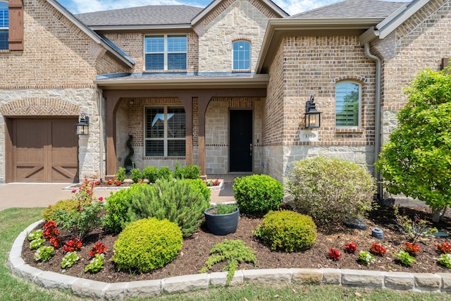 view of exterior entry featuring a garage, stone siding, and brick siding