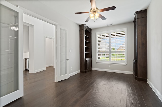 unfurnished room with baseboards, ceiling fan, dark wood finished floors, and visible vents