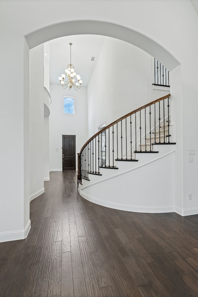 foyer entrance with stairway, baseboards, a notable chandelier, a high ceiling, and hardwood / wood-style floors