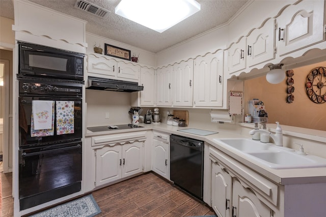 kitchen featuring visible vents, dark wood finished floors, a sink, black appliances, and under cabinet range hood