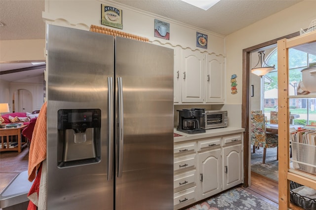 kitchen with stainless steel fridge, light countertops, a textured ceiling, and white cabinetry