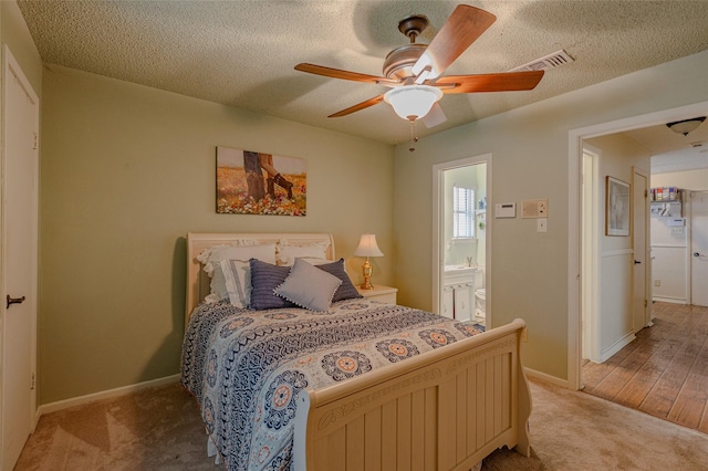 bedroom featuring light carpet, a ceiling fan, baseboards, ensuite bathroom, and visible vents