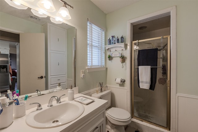 bathroom with visible vents, a stall shower, vanity, a wainscoted wall, and toilet