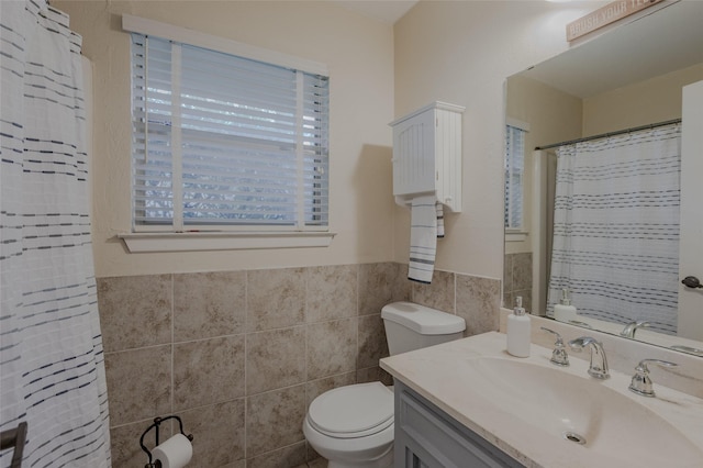 bathroom with vanity, toilet, a shower with shower curtain, a wainscoted wall, and tile walls