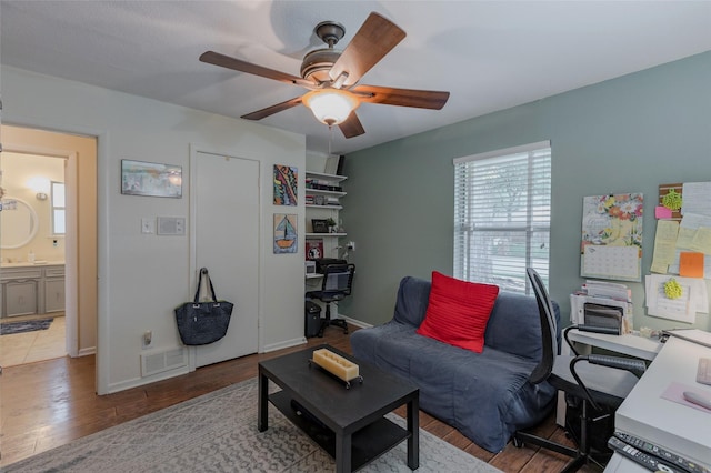office area with baseboards, a ceiling fan, wood finished floors, and visible vents