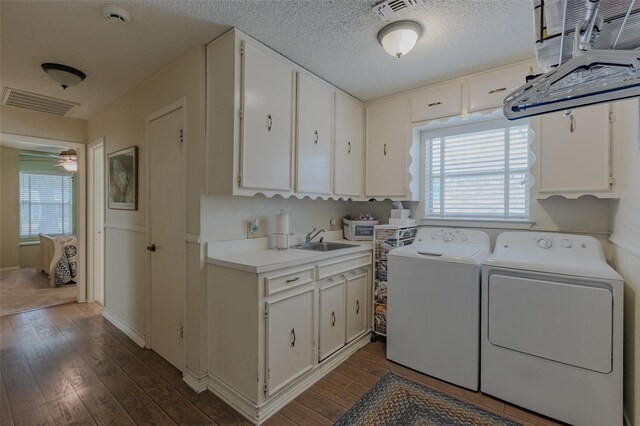 laundry room with independent washer and dryer, visible vents, dark wood finished floors, cabinet space, and a sink