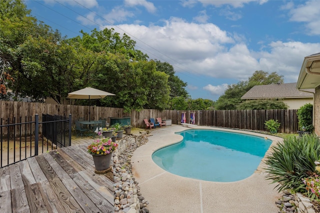 view of swimming pool featuring a fenced in pool, a fenced backyard, and a deck